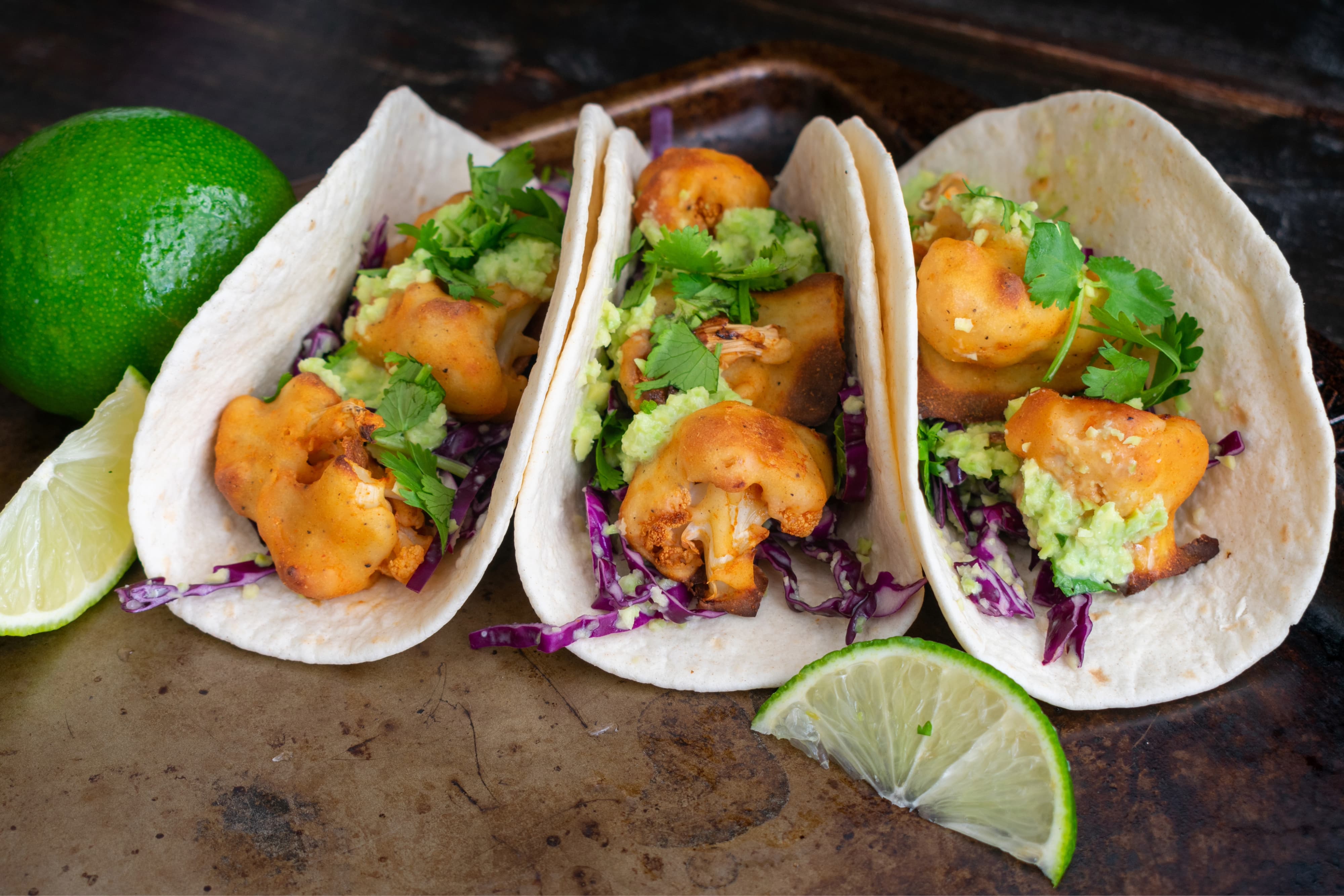Vegetarian tacos made with spicy cauliflower, avocado crema, and shredded cabbage