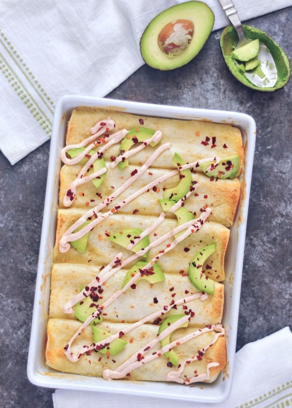 A white dish holds avocado and cheese enchiladas, a delectable Mexican dish with creamy fillings