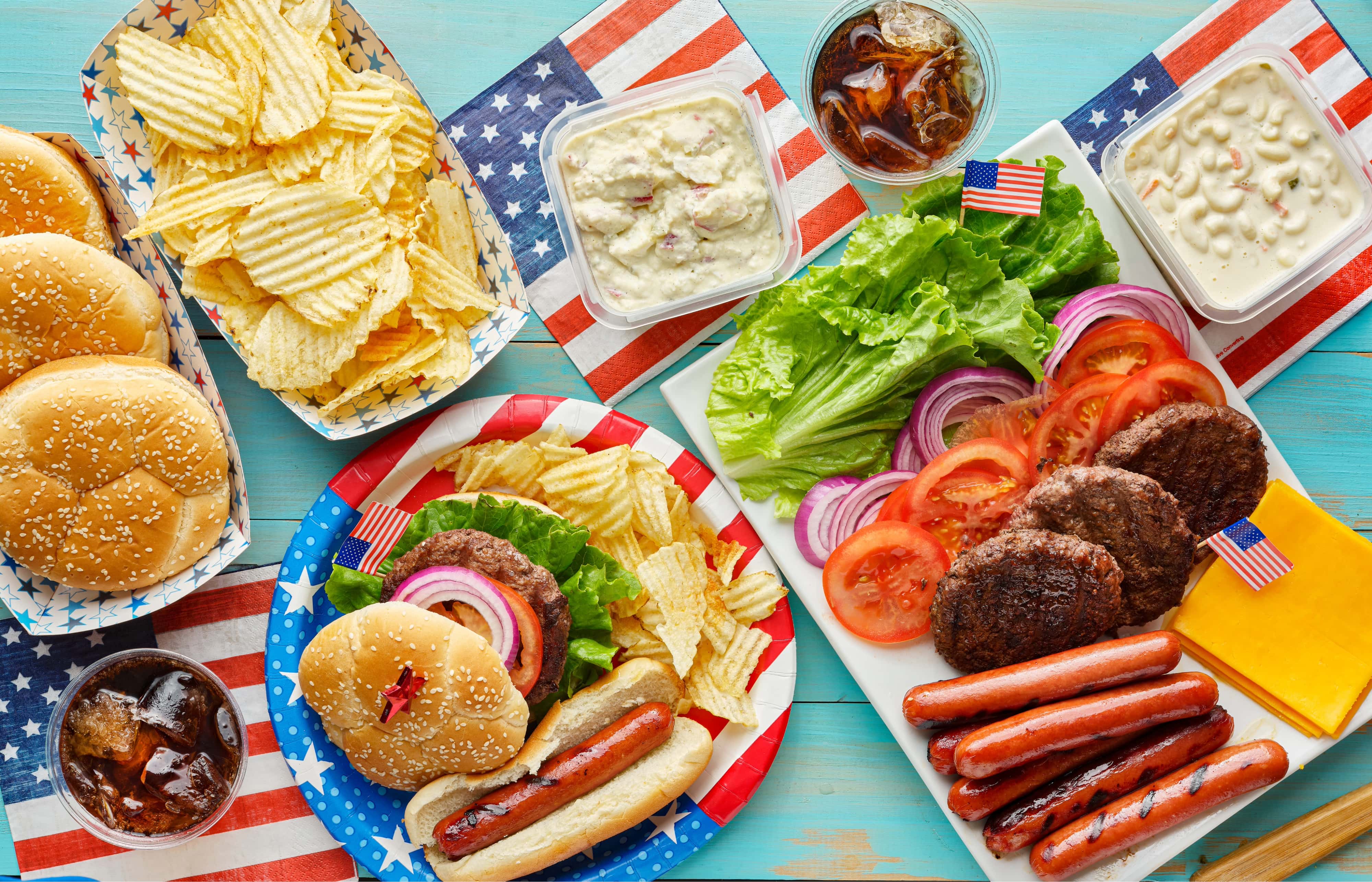 4th of july feast with burgers and hot dogs on picnic table