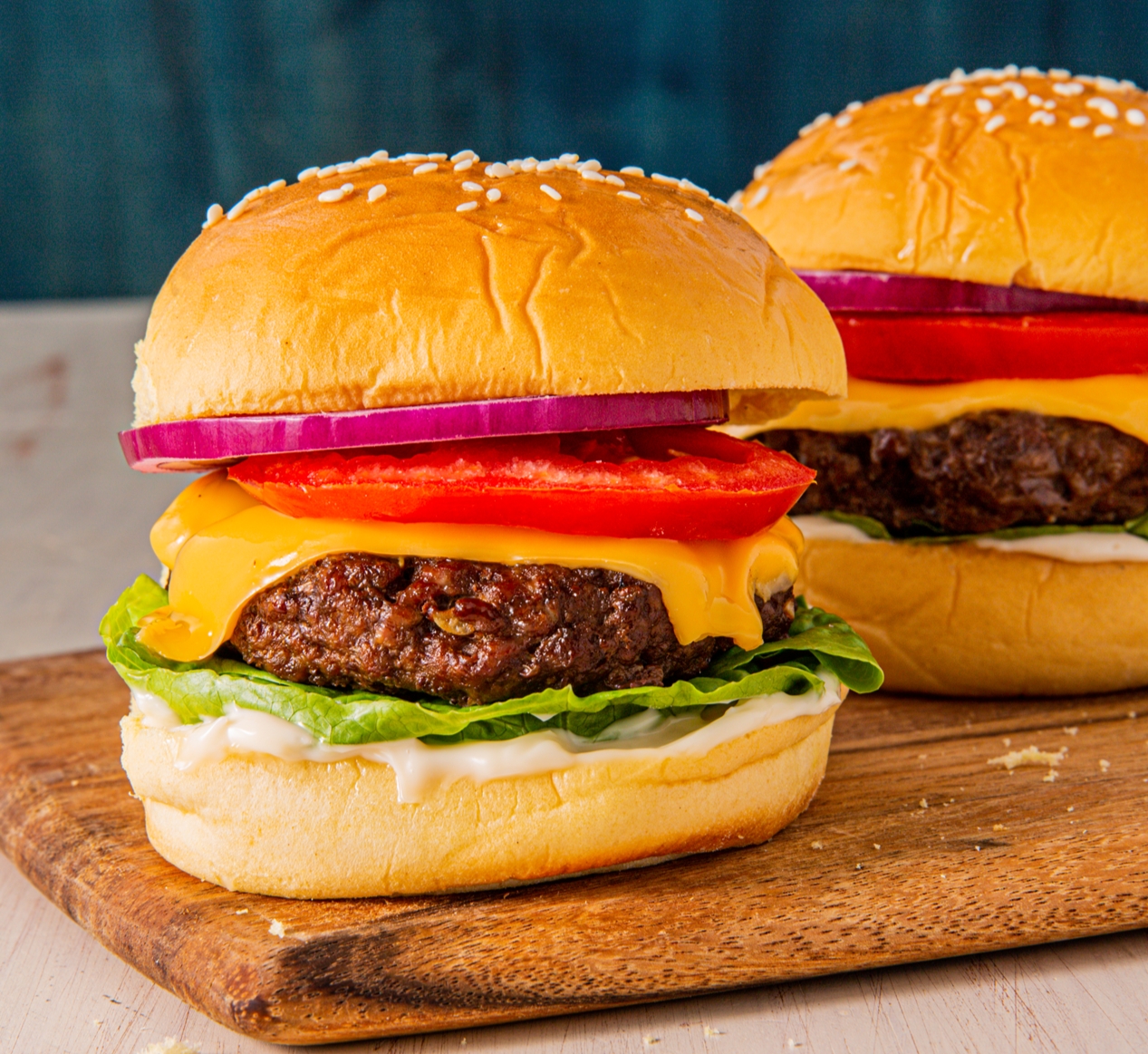 Two hamburgers placed on a wooden cutting board