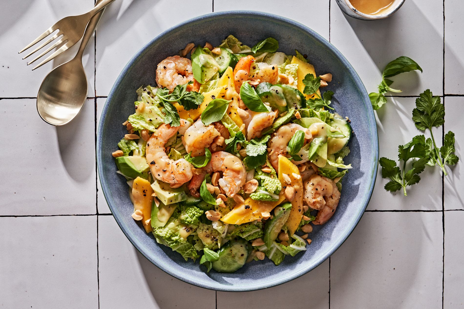 Image of a salad bowl with shrimp, avocado, and veggies on a table