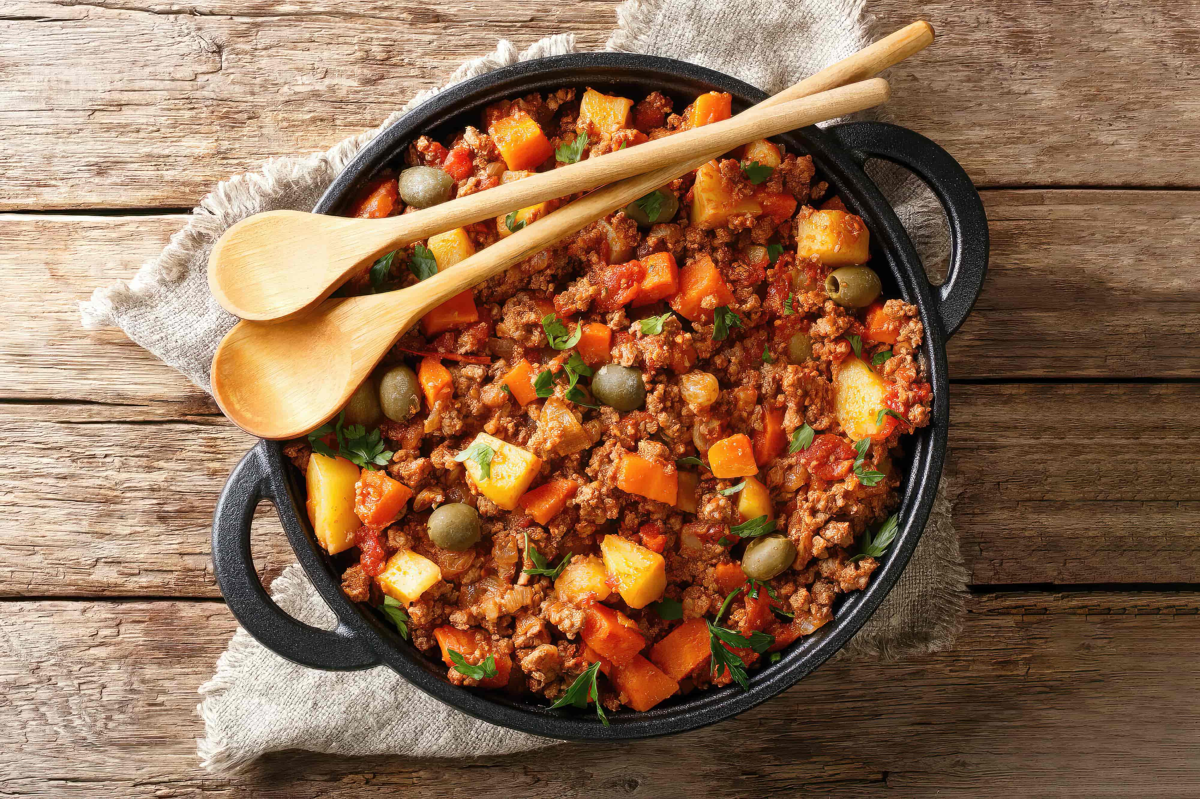 Delicious Picadillo cooked from ground beef with vegetables, raisins and spices close-up in a frying pan