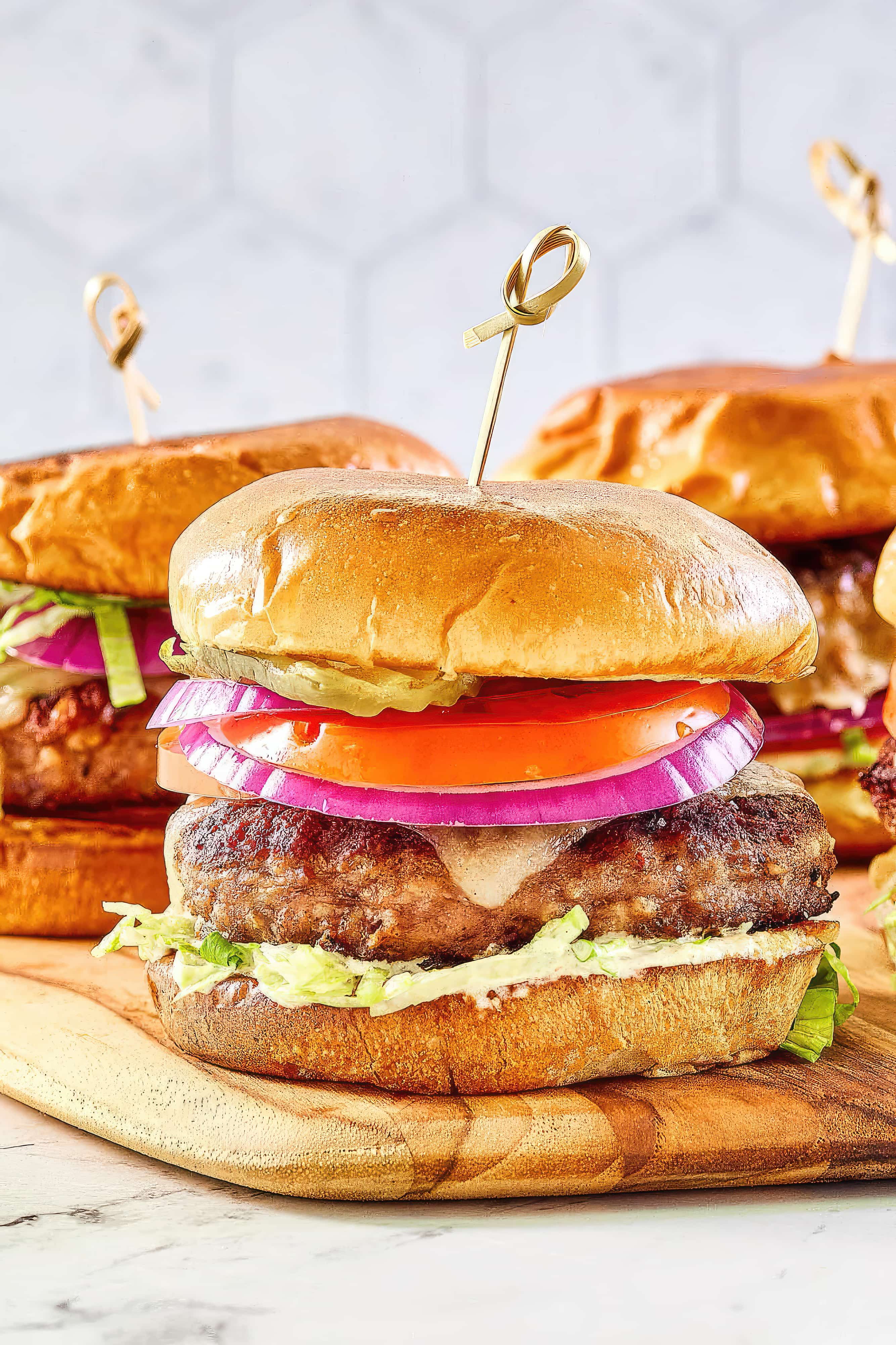 Assorted hamburgers neatly arranged on a wooden cutting board, showcasing their savory fillings and fresh ingredients