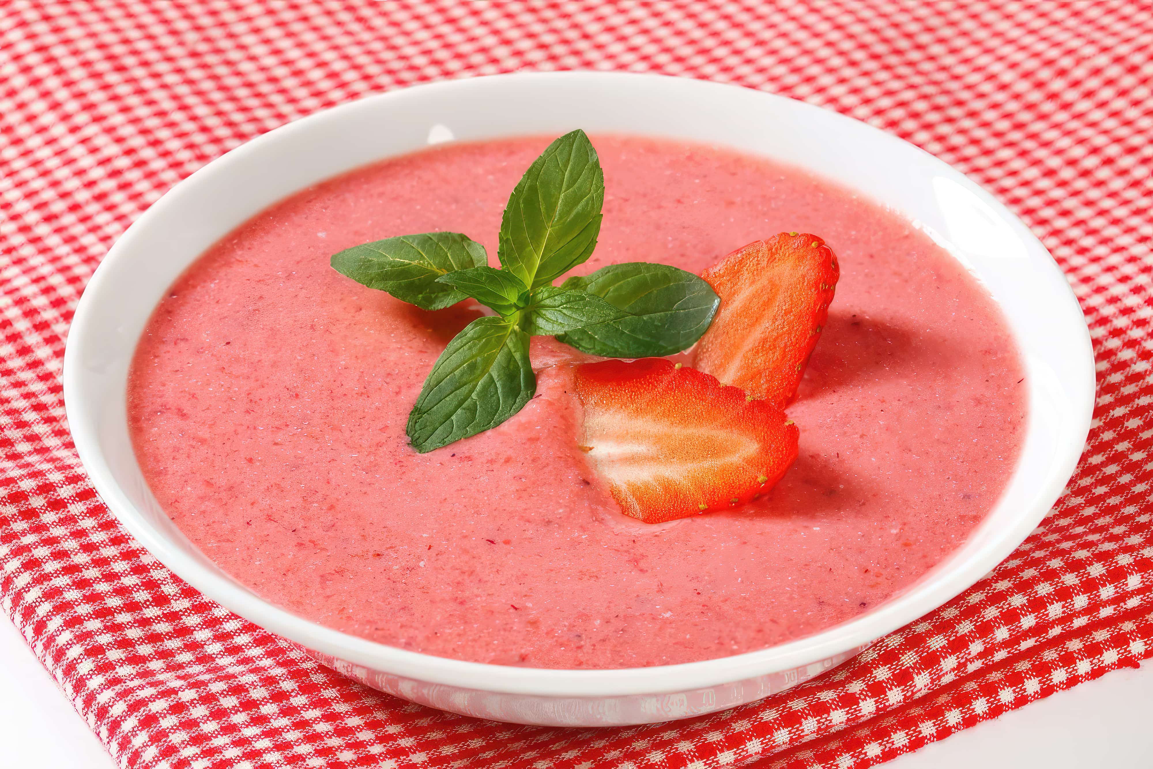 A bowl of strawberry soup garnished with a strawberry